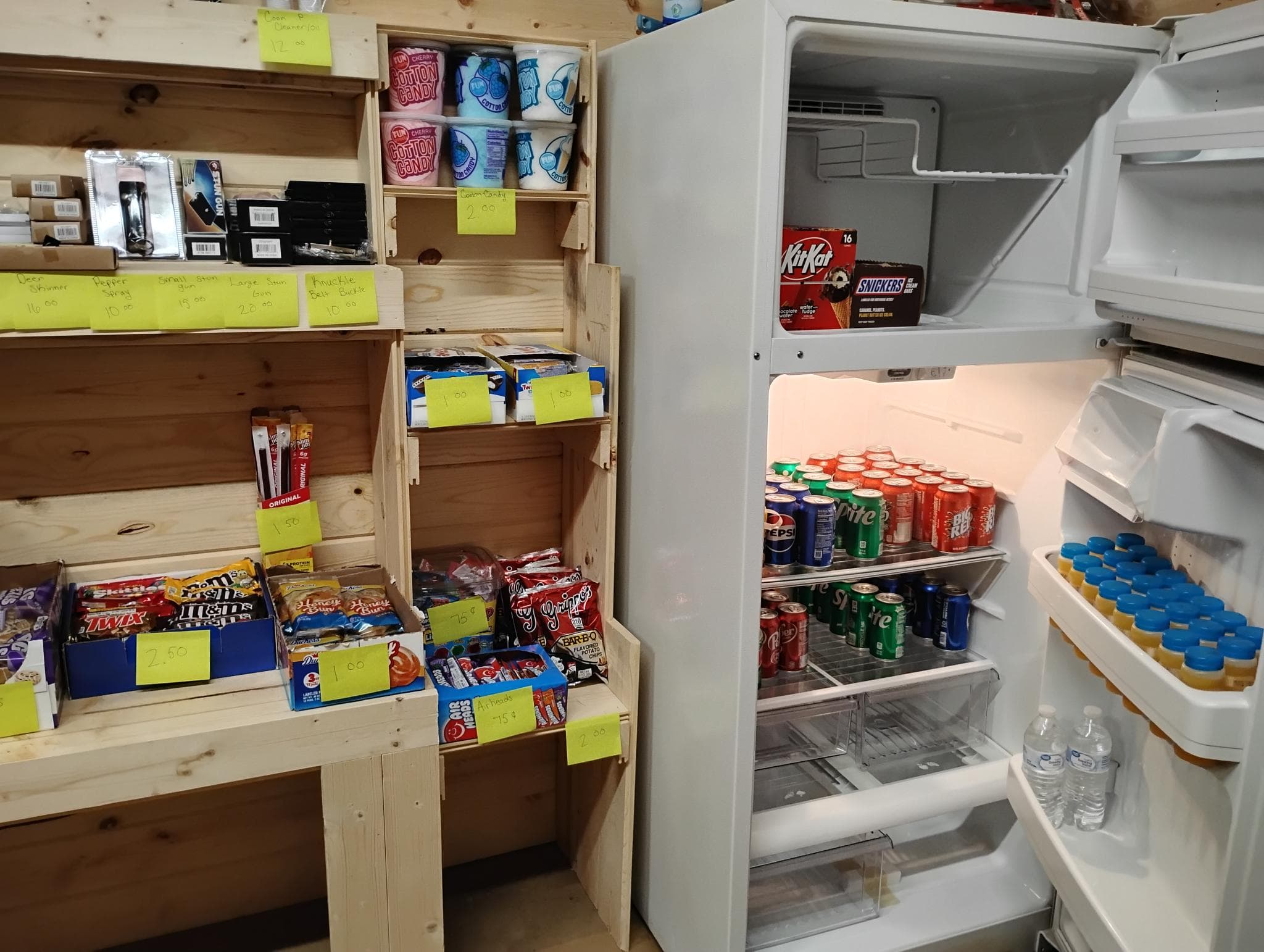 Counter shelves of candy, cotton candy, and an open fridge full of cold drinks.