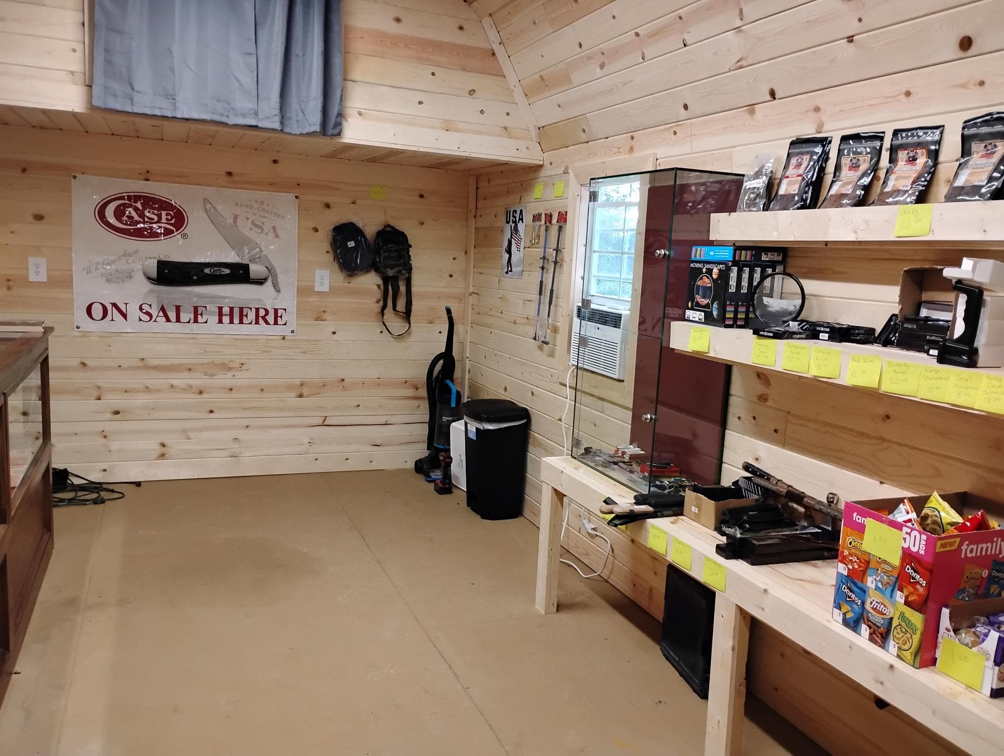Inside the shop — pine-board walls, glass display case, Case ON SALE HERE banner.