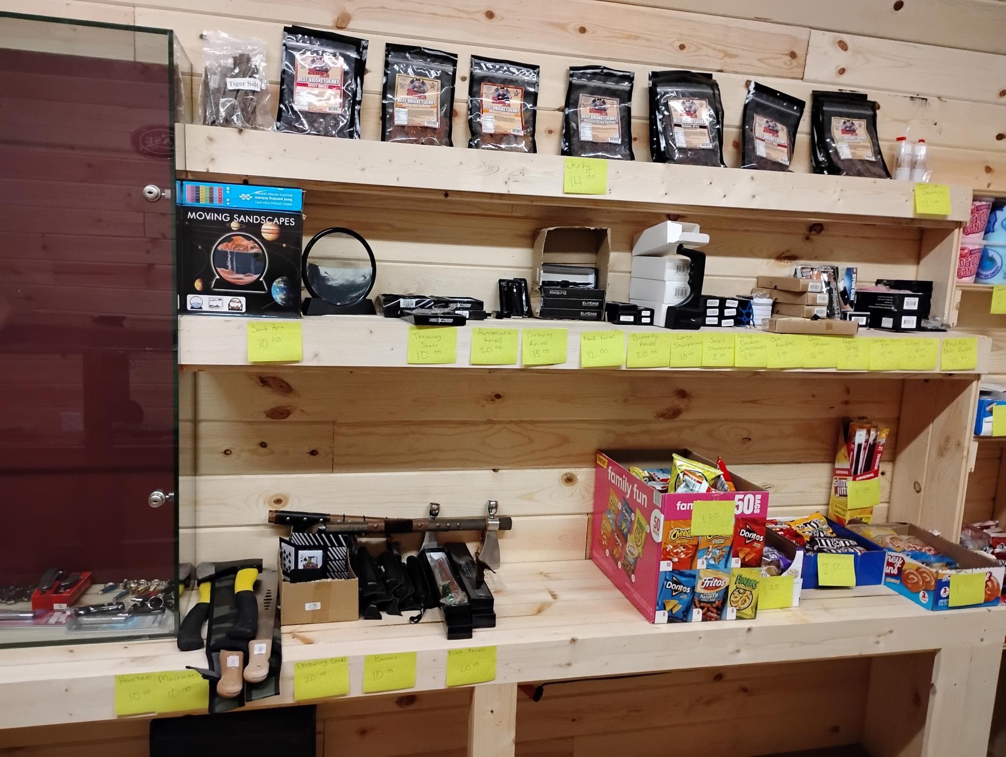 Wall shelves with bagged jerky, small electronics, and snack-size chip boxes.
